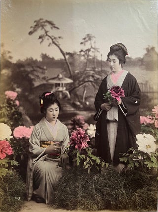 1914 Japan – Two young geishas in flower garden, studio photograph. Kazumasa / Original...